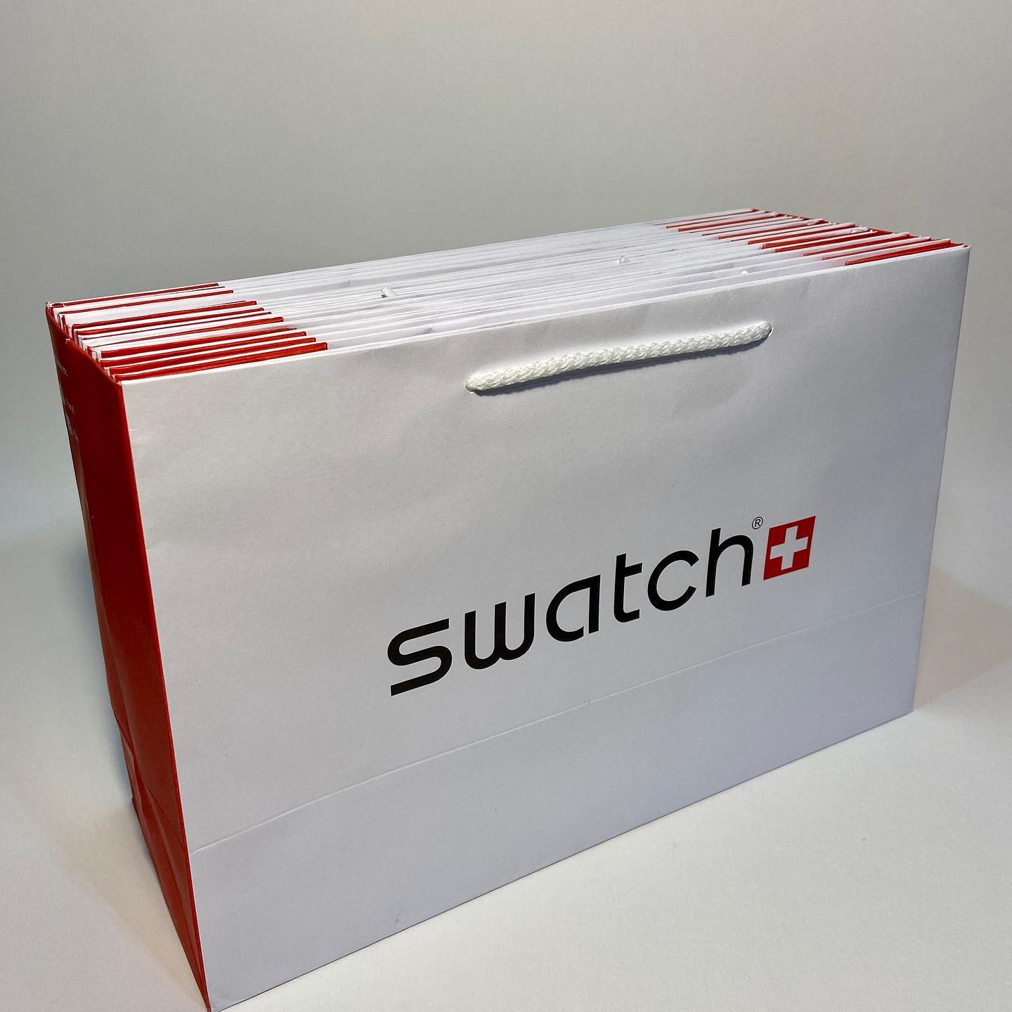 Un bolso de muestrario blanco y rojo con asa de cuerda