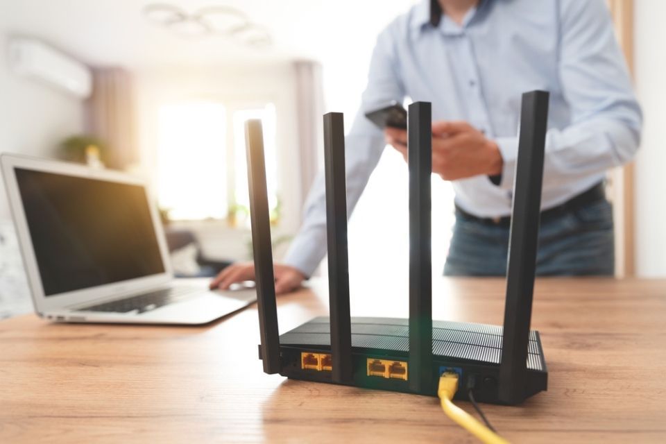 Modern WI-FI router on light table in room. Man using fast internet
