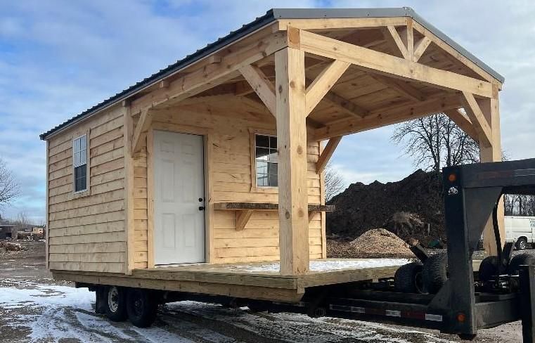 A small wooden house is being transported on a trailer.