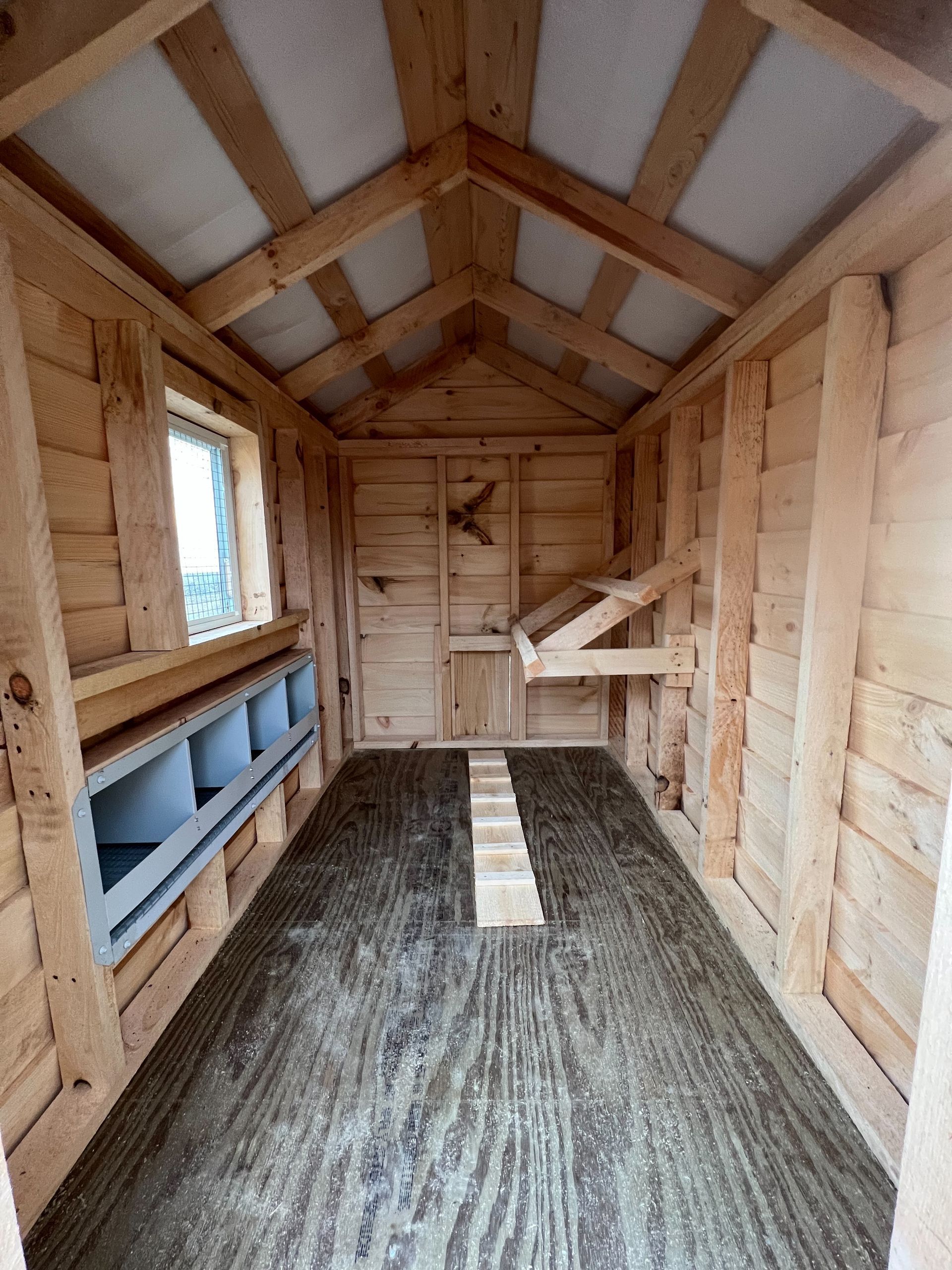 The inside of a wooden chicken coop with a window