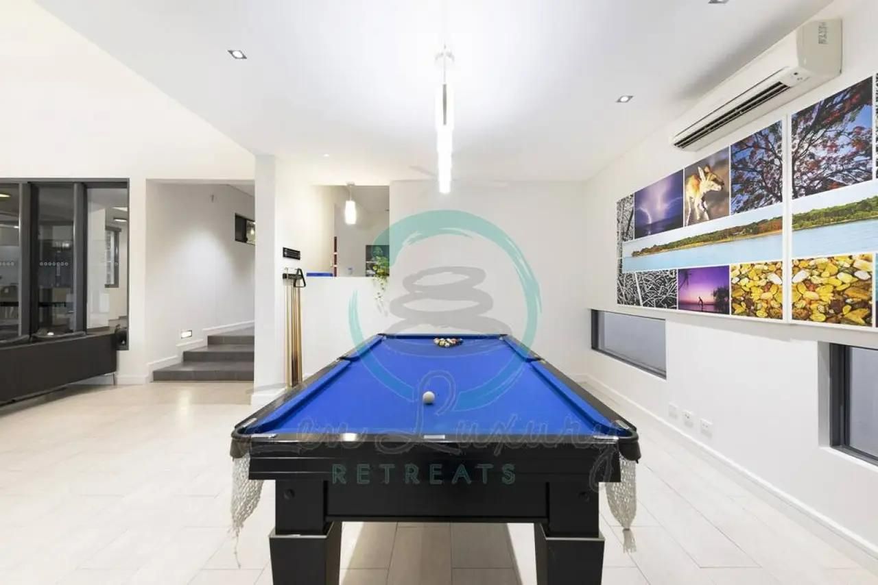 A Pool Table in a Room With Pictures on the Wall — Zen Luxury Retreats in Darwin City, NT