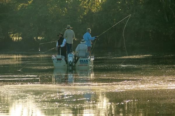 A Group of People Are Fishing in a River From a Boat — Zen Luxury Retreats in Darwin City, NT