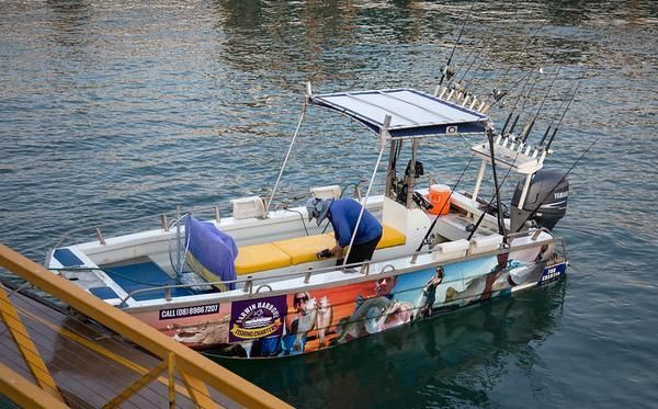 A Boat With Fishing Rods Attached to It is in the Water — Zen Luxury Retreats in Darwin City, NT