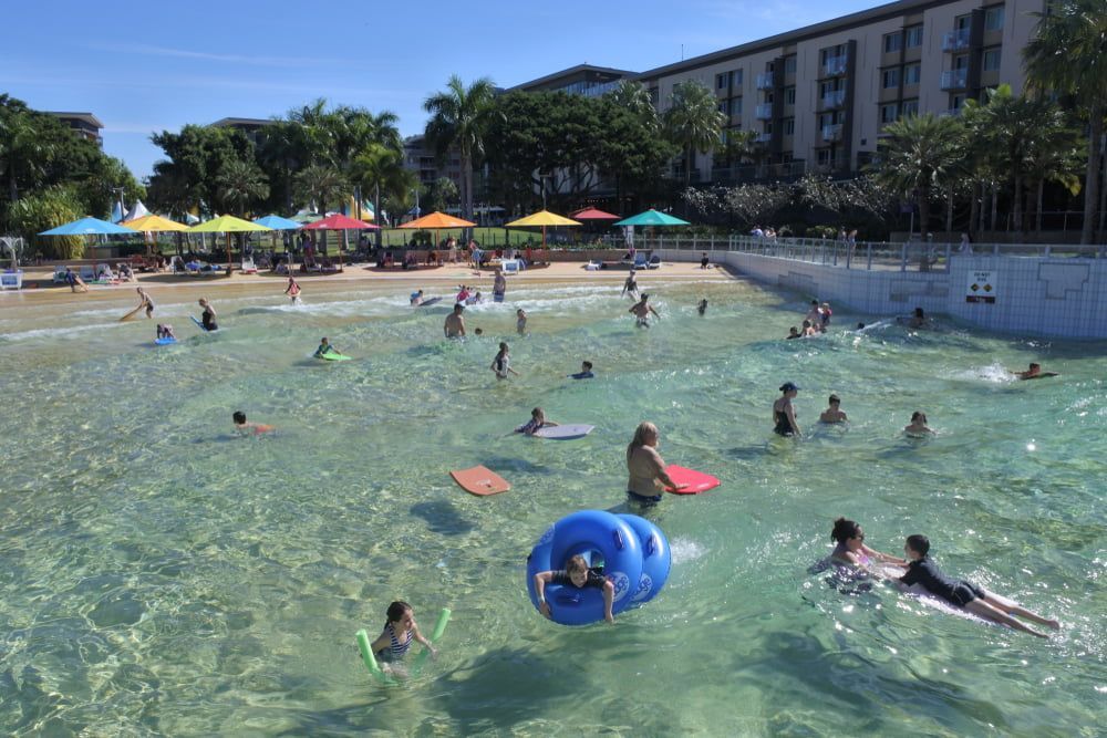 A Group of People Are Swimming in A Pool — Zen Luxury Retreats in Darwin City, NT