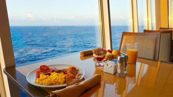 A Plate of Food is on a Table in Front of a Window Overlooking the Ocean — Zen Luxury Retreats in Darwin City, NT