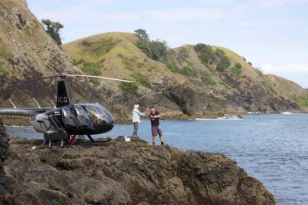 A Helicopter is Parked on a Rocky Cliff Overlooking a Body of Water — Zen Luxury Retreats in Darwin City, NT