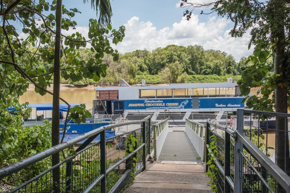 A Bridge Leading to A Boat on A River Surrounded by Trees — Zen Luxury Retreats in Darwin City, NT