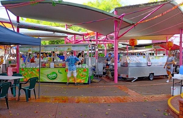 A Man Is Standing in Front of A Food Stand at A Market — Zen Luxury Retreats in Darwin City, NT