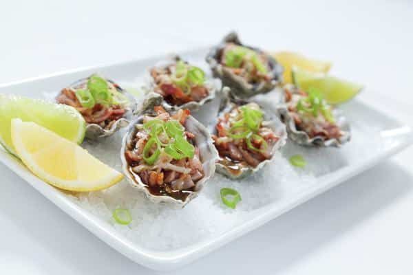 A White Plate Topped with Oysters and Lemon Slices — Zen Luxury Retreats in Darwin City, NT