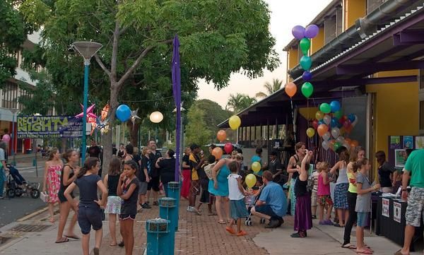 A Group of People Are Standing on A Sidewalk in Front of A Building with Balloons — Zen Luxury Retreats in Darwin City, NT