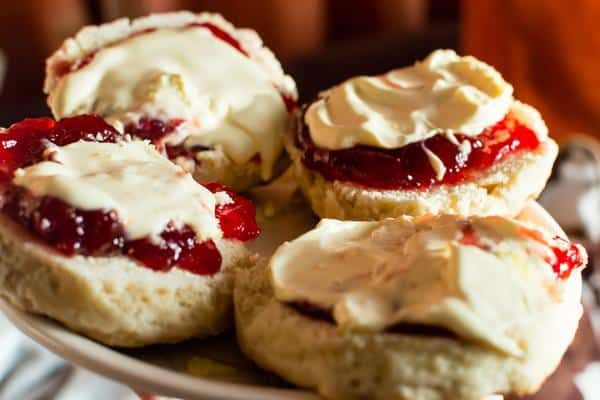 A White Plate Topped with Four Scones with Jam and Whipped Cream — Zen Luxury Retreats in Darwin City, NT