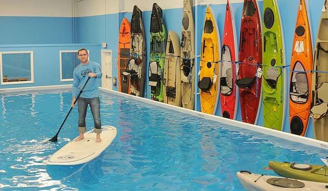 Worker Standing on a Paddle Board in a Large Pool — Zen Luxury Retreats in Darwin City, NT