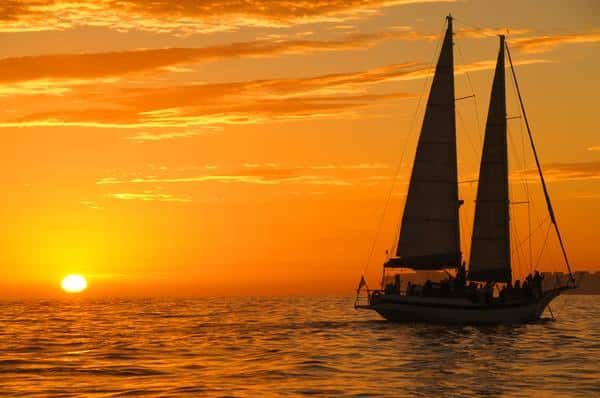 A Sailboat Is Floating in The Ocean at Sunset — Zen Luxury Retreats in Darwin City, NT