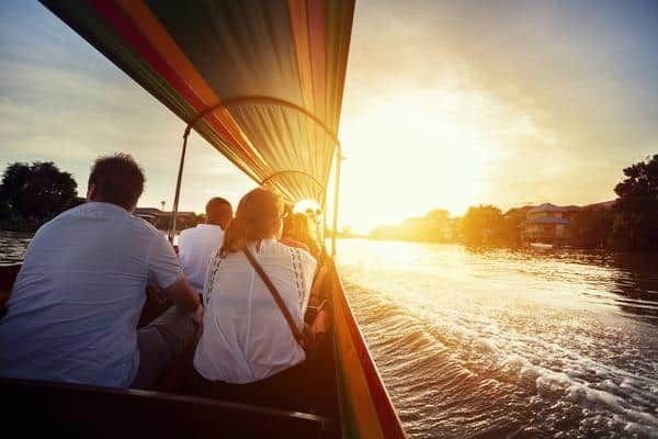 A Group of People Are Riding a Boat on A River at Sunset — Zen Luxury Retreats in Darwin City, NT