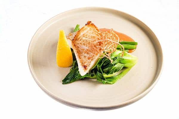 A White Plate Topped with A Piece of Meat and Vegetables on A White Background — Zen Luxury Retreats in Darwin City, NT