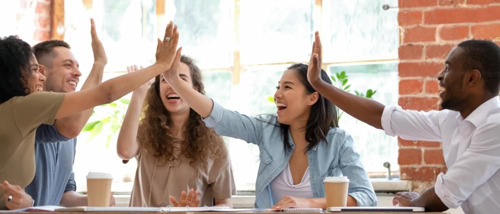 Group of People Are Giving Each her a High Five While Sitting at a Table — Serenity Strides Redbank in Plains, QLD