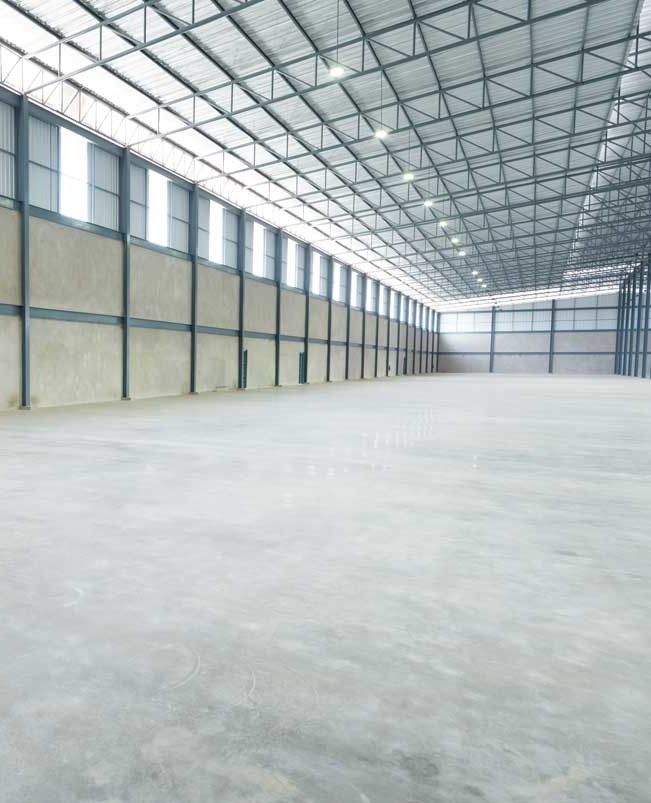 An empty warehouse with a concrete floor and a metal roof.
