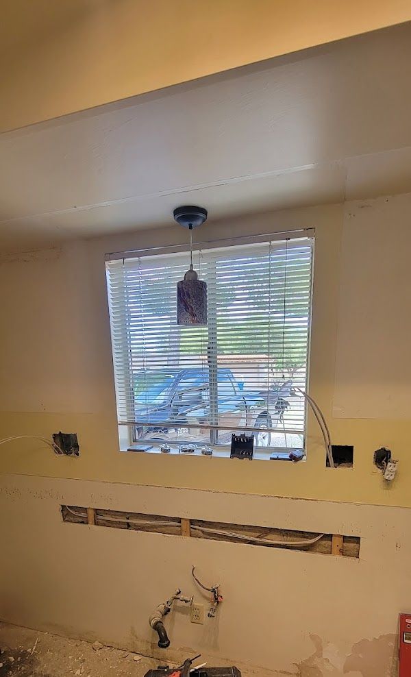 A kitchen under construction with a window and blinds.