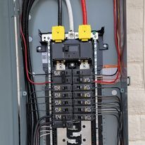 A close up of a electrical panel with a lot of wires coming out of it.