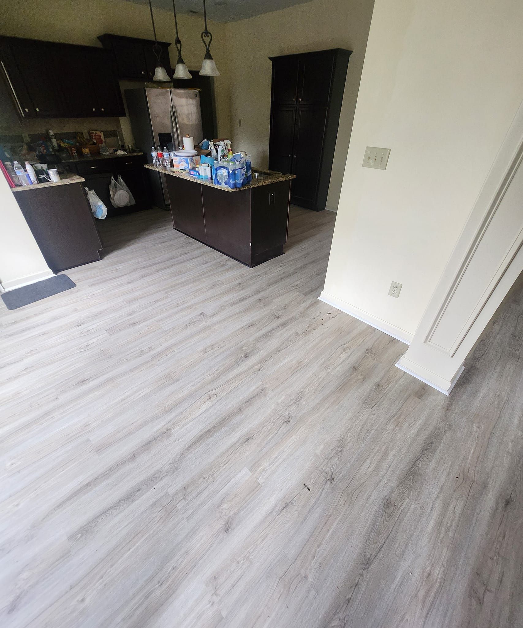 Kitchen with light wood-look flooring, dark cabinetry, and a dark brown island. Beige walls.