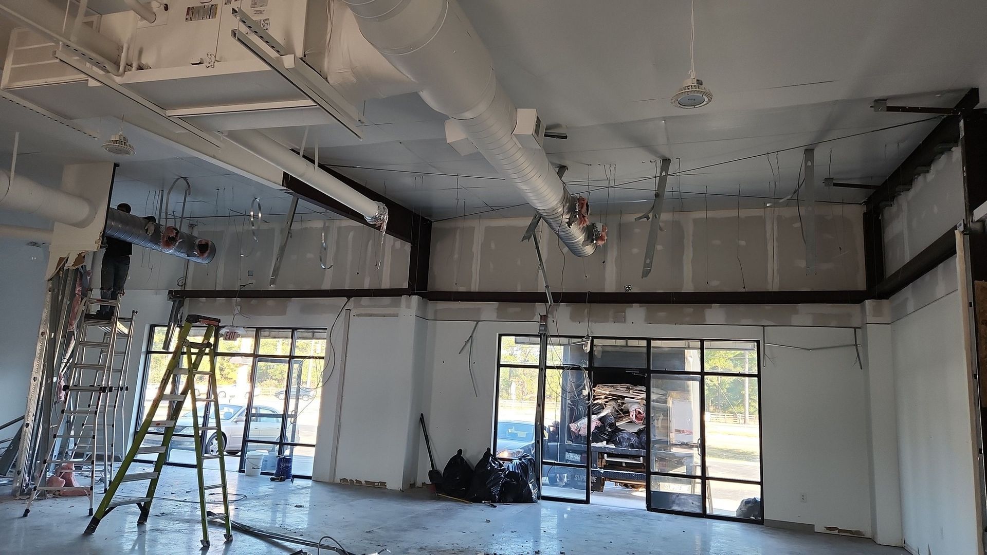 Interior construction site with ladder, exposed beams, and unfinished walls.