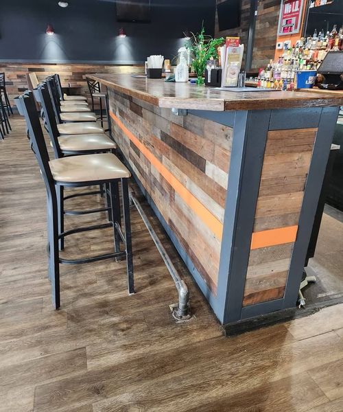 Bar with wood and metal front, high stools, and stainless steel foot rail.