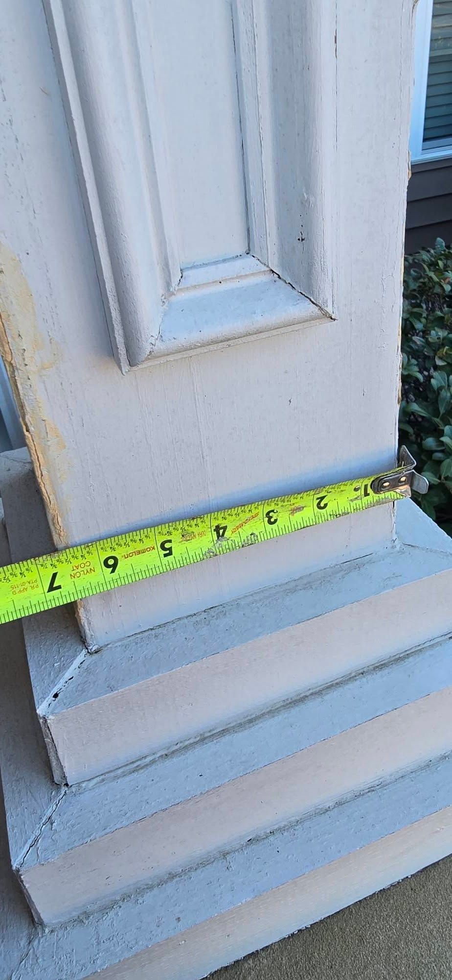 A white-painted column base is measured with a yellow tape measure showing about 4 inches.