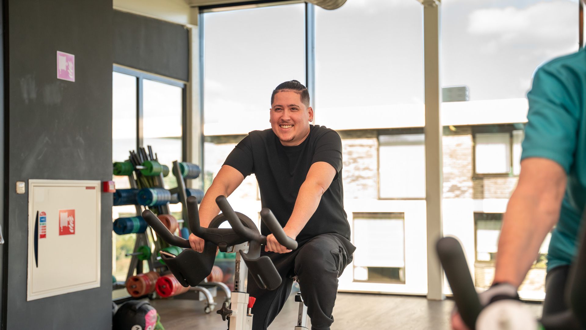 Een man fietst op een hometrainer in een sportschool.