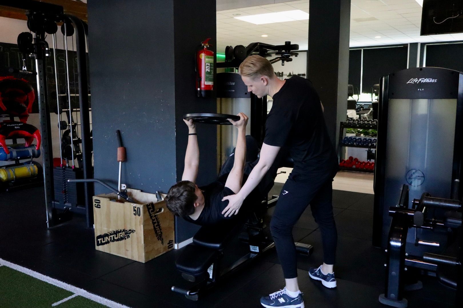 Een sportschool vol met fitnessapparatuur en televisies.