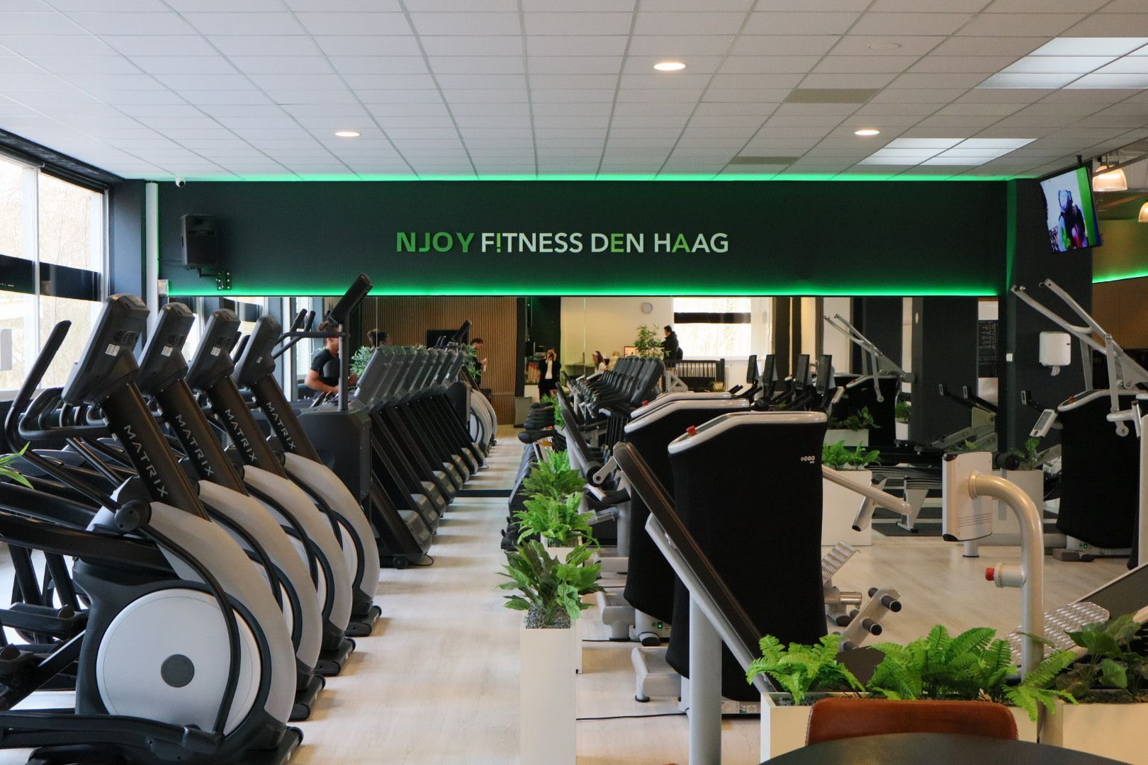 Een sportschool vol met fitnessapparatuur en televisies.