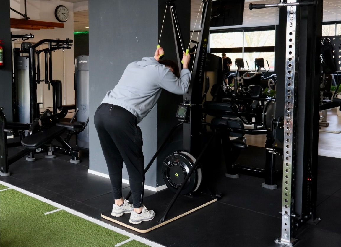 Een sportschool vol met fitnessapparatuur en televisies.