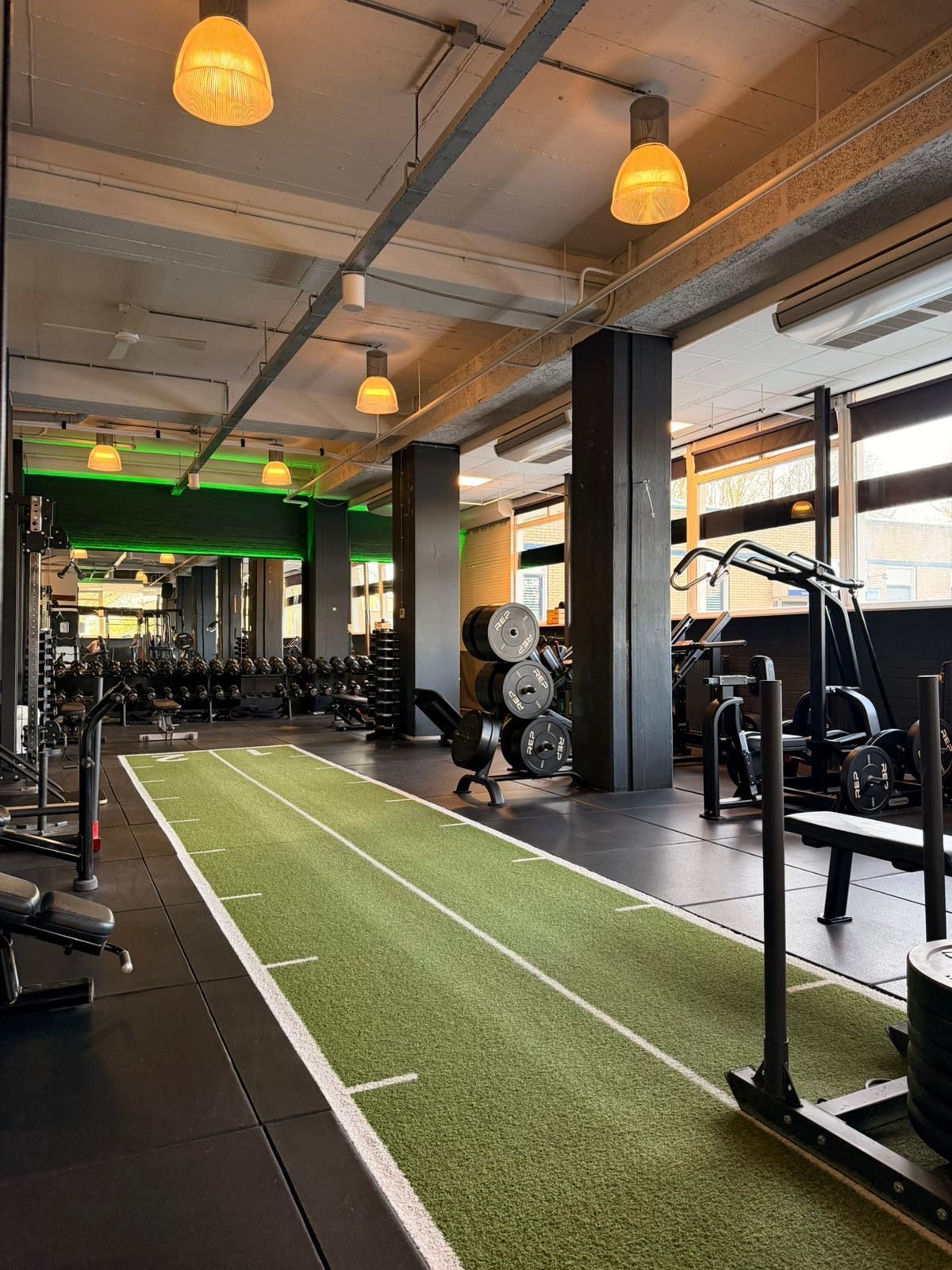 Een sportschool vol met fitnessapparatuur en televisies.