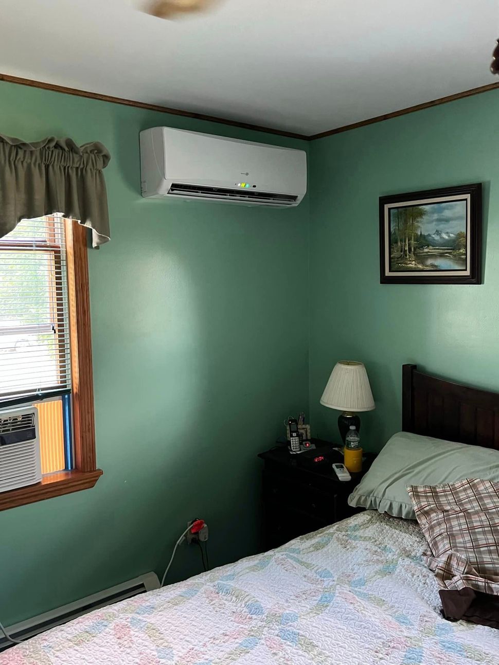 a bedroom with a bed , nightstand , lamp and air conditioner .