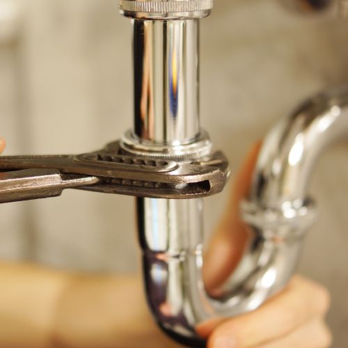 A person is fixing a pipe with a wrench