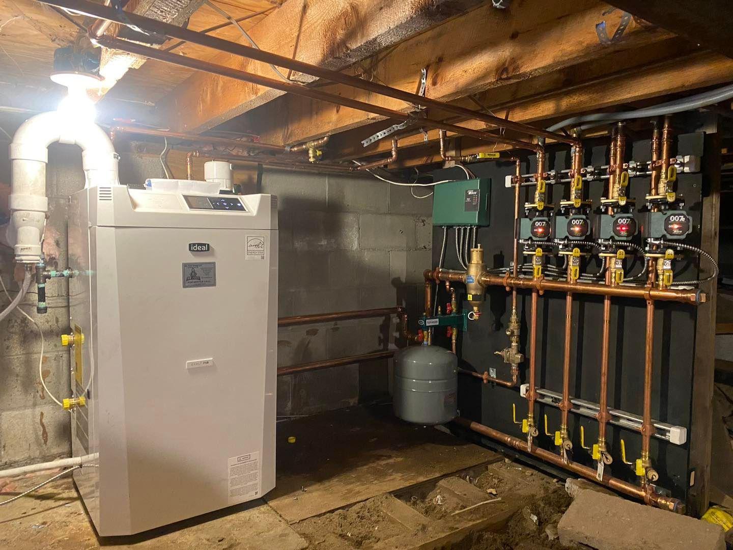 A large white boiler is sitting in a basement next to a bunch of pipes.