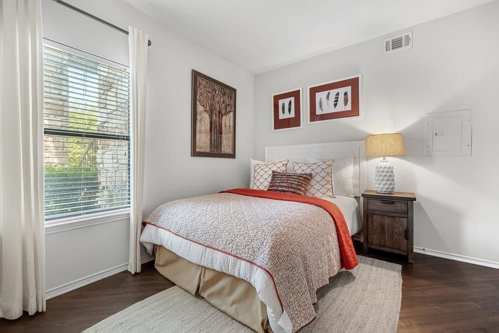 a bedroom with a bed, nightstand, lamp, and window at Marquis at Caprock Canyon in Austin, TX.