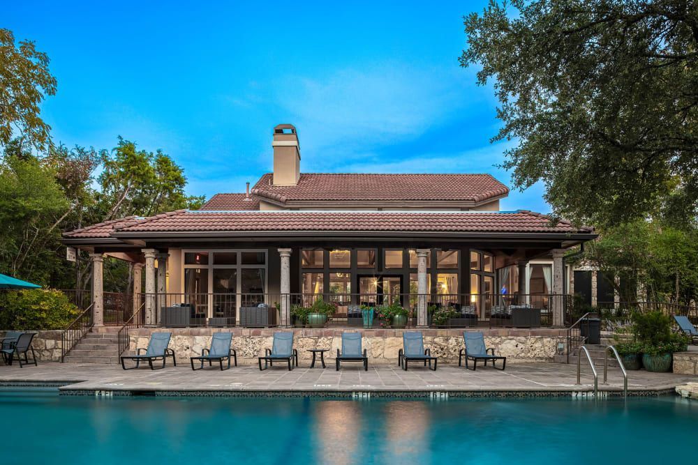 the clubhouse with a swimming pool in front of it at Marquis at Caprock Canyon in Austin, TX.
