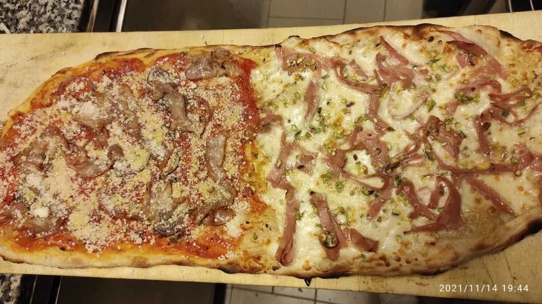 Due pizze rettangolari lunghe su un tagliere di legno, una con salsa di pomodoro e formaggio, l'altra leggermente condita con salsa ed erbe aromatiche.