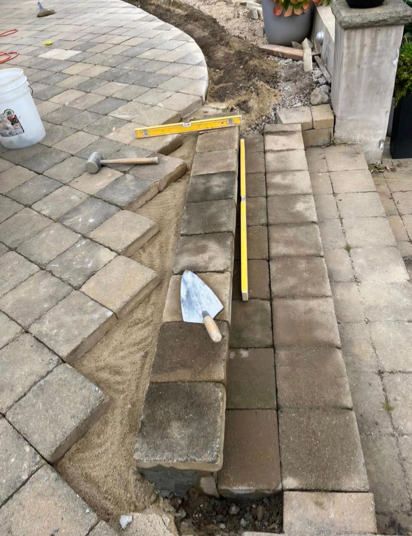 Brick patio steps under construction, with tools and materials visible.