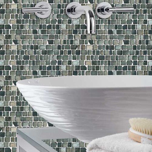 A bathroom sink with a mosaic wall behind it