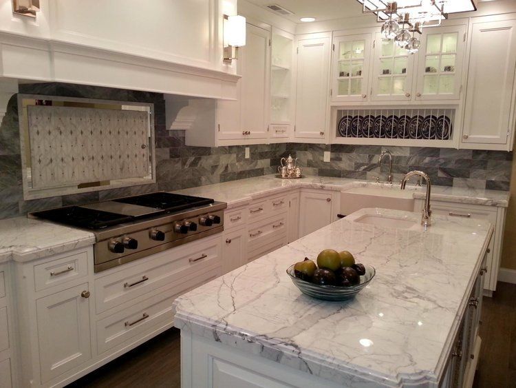 A kitchen with white cabinets and marble counter tops