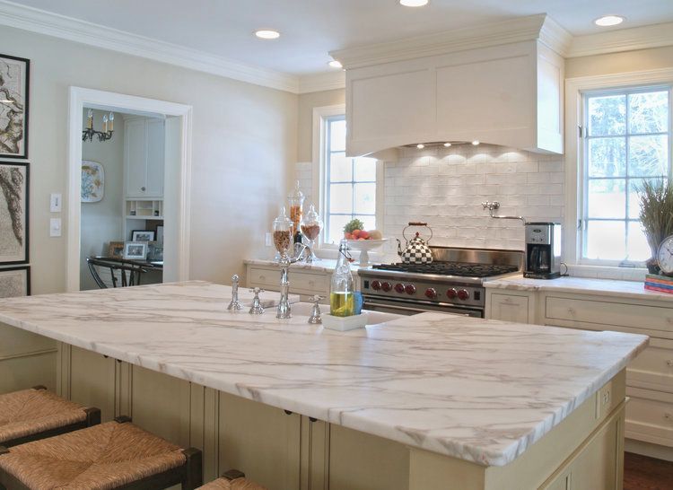 A kitchen with a large island and marble counter tops