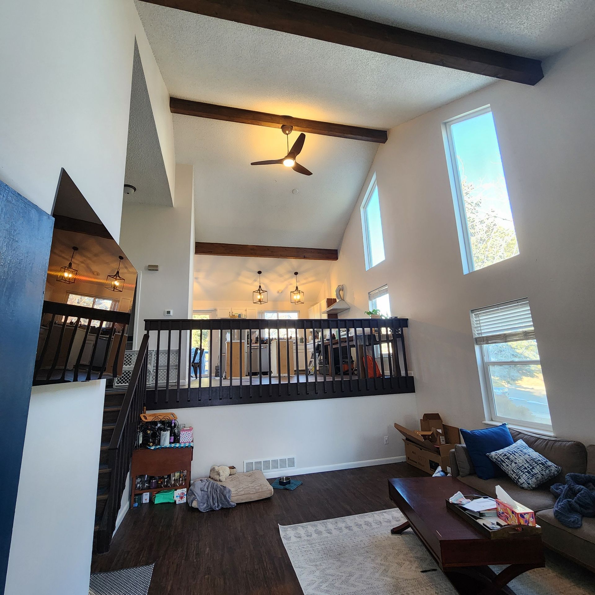 A living room with a balcony and a ceiling fan