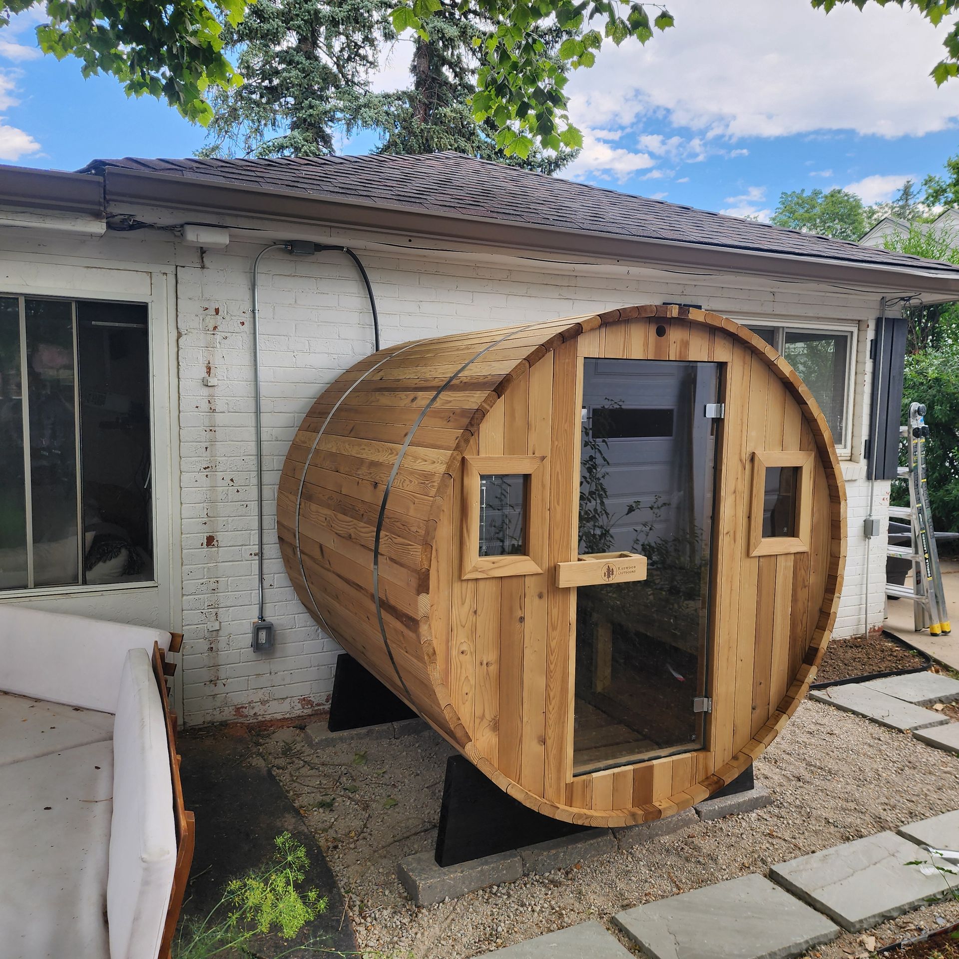 A wooden barrel with a glass door is in front of a house