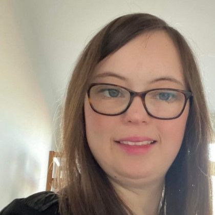 A woman wearing glasses is smiling for the camera.