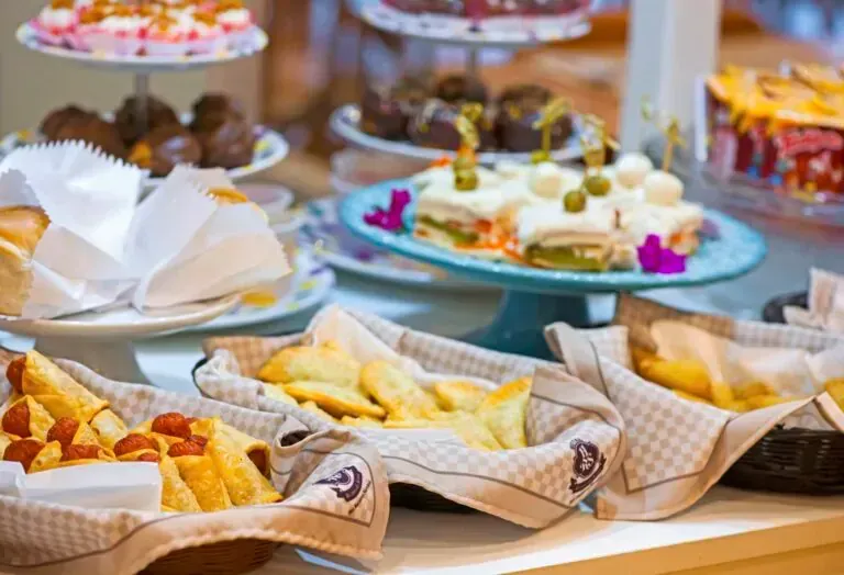 Mesa de bufê com diversos doces, sanduíches e sobremesas.