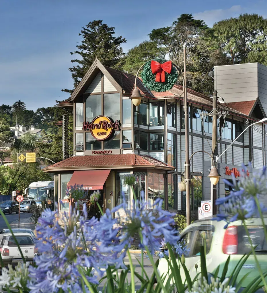 Edifício do Hard Rock Cafe com guirlanda de Natal, toldo vermelho e flores azuis em primeiro plano.