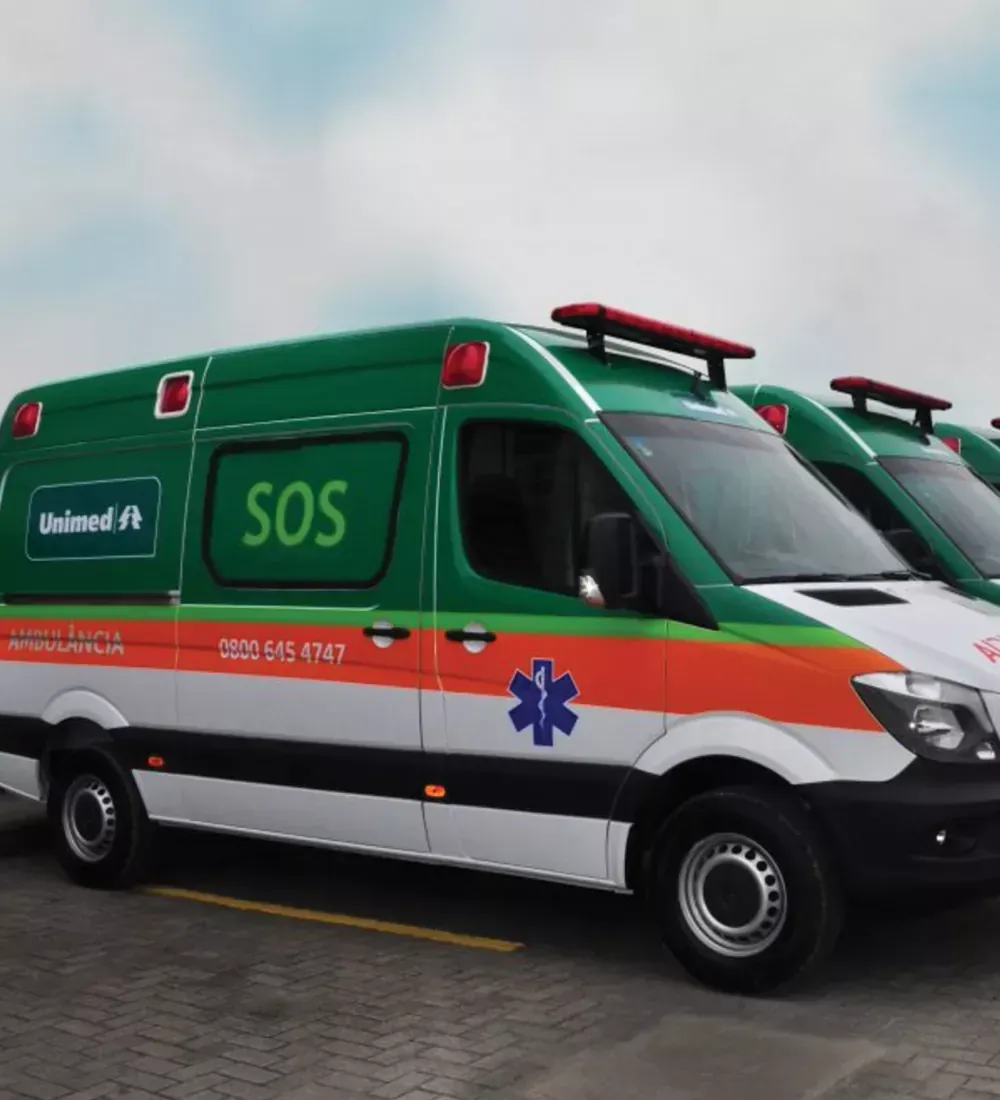 Ambulância Unimed verde e branca, luzes vermelhas, inscrição SOS, estrela médica azul.