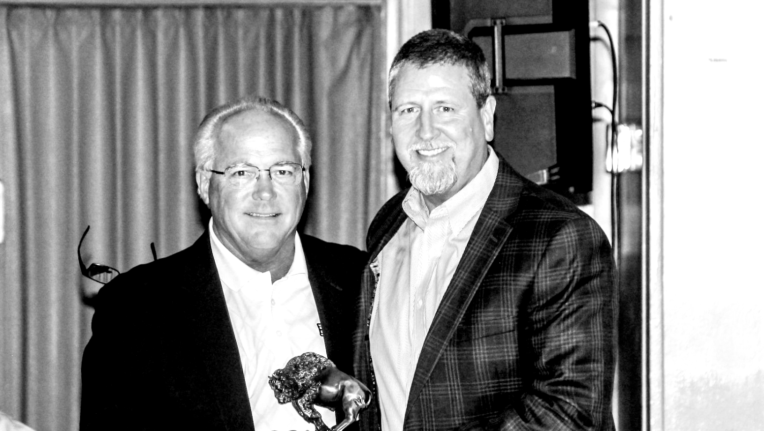 two men in suits are shaking hands in a black and white photo