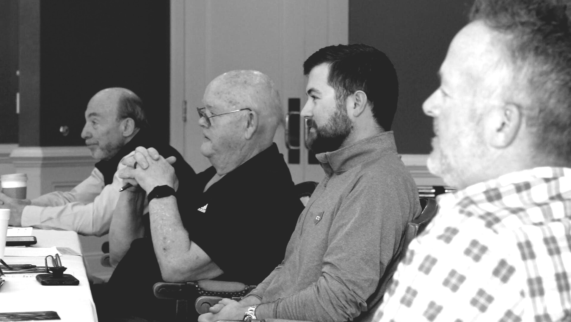 a group of men are sitting at a table in a black and white photo